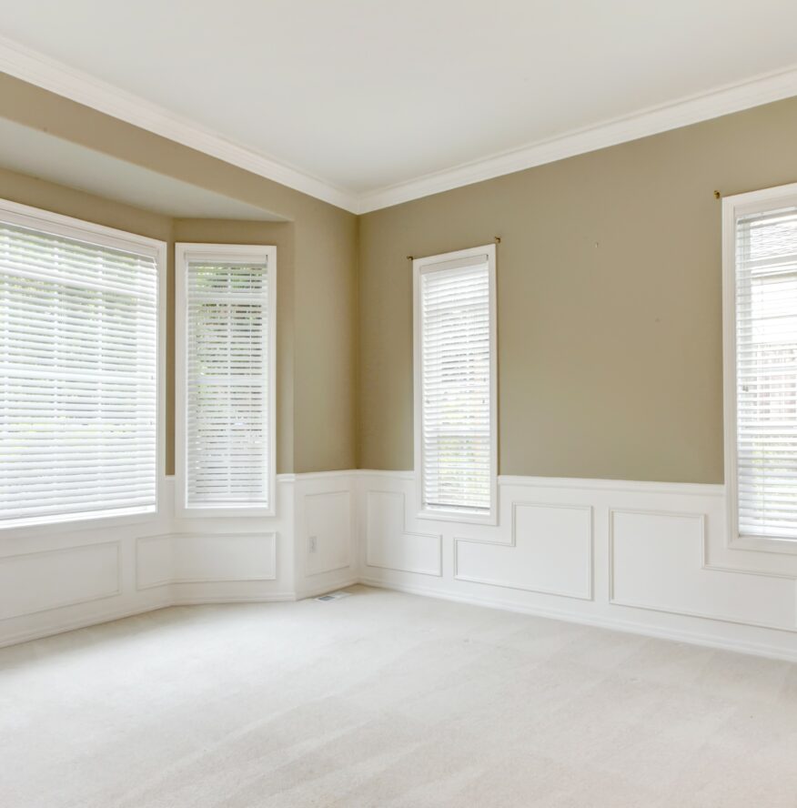 Bright large empty room with carpet, molding and  windows.